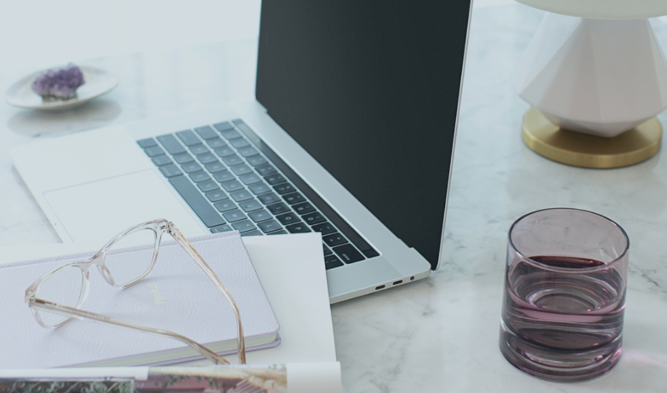 MacBook with Glass of Water and Writing Materials